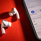 A decorative image of AirPods Pro on a table next to an iPhone displaying the bluetooth settings